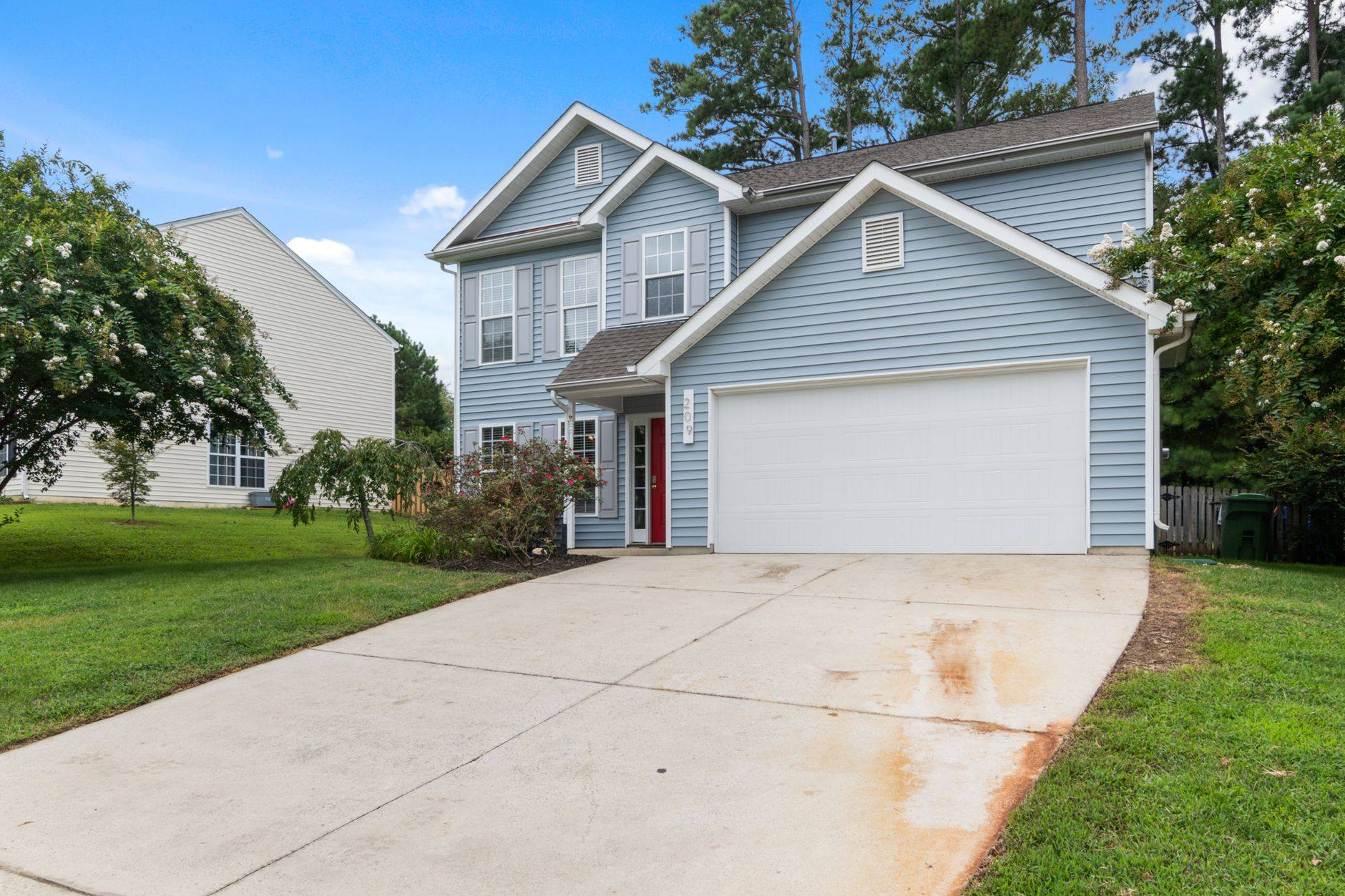 Blue two-story house with a front porch on a quiet Texas residential street
