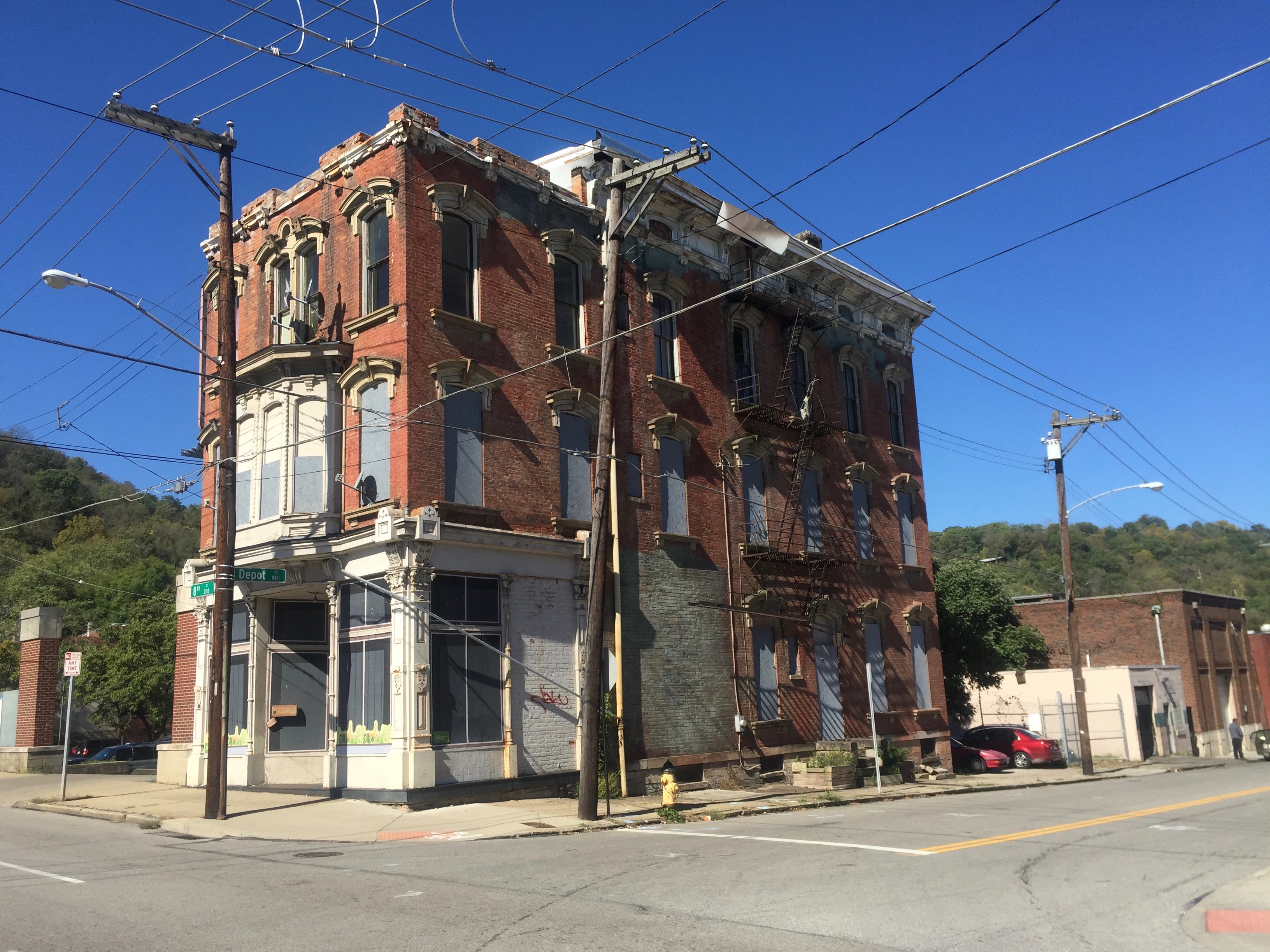 Older brick corner building with boarded windows awaiting renovation