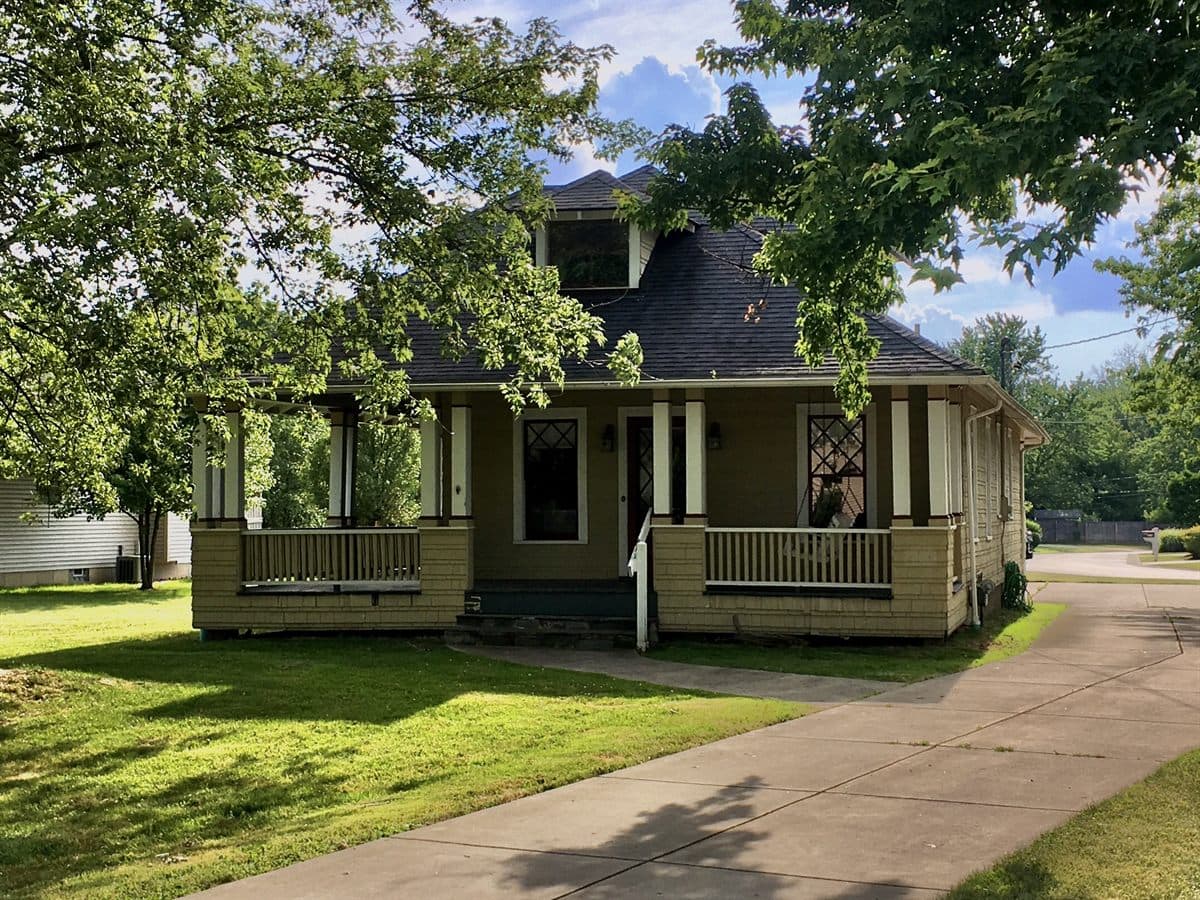 Craftsman bungalow house with a wraparound front porch on a sunny day