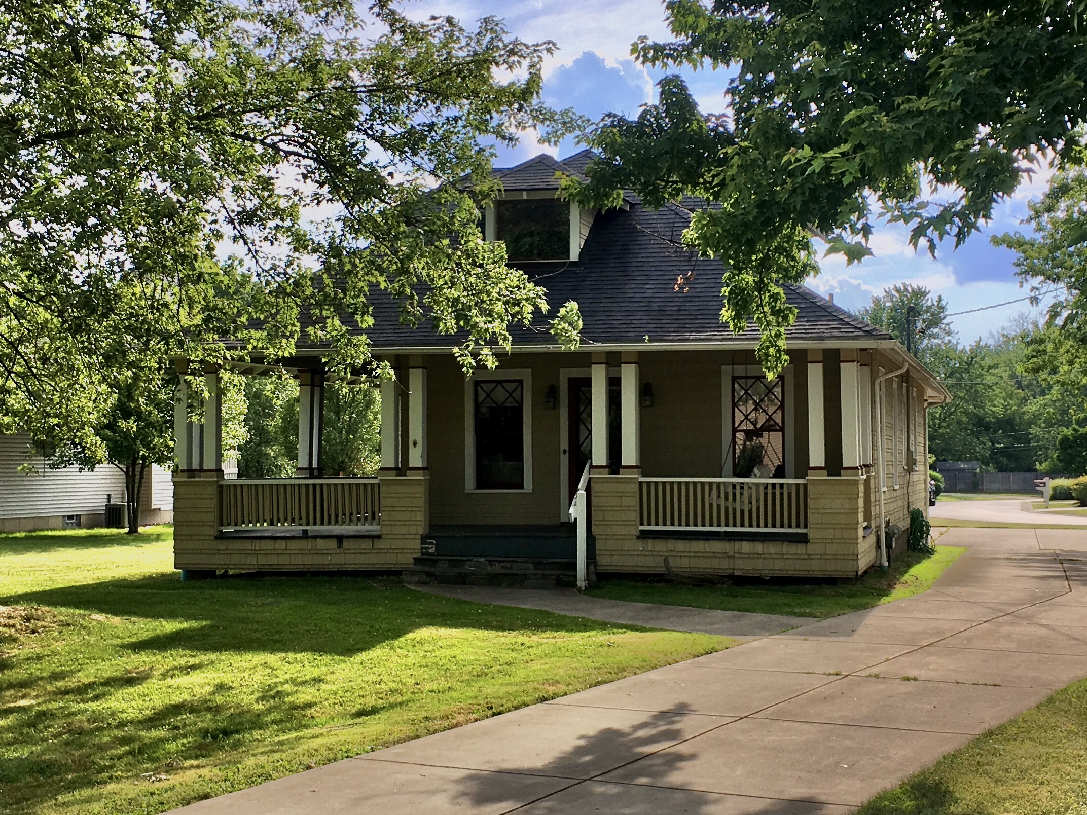 Craftsman bungalow house with a wraparound front porch on a sunny day