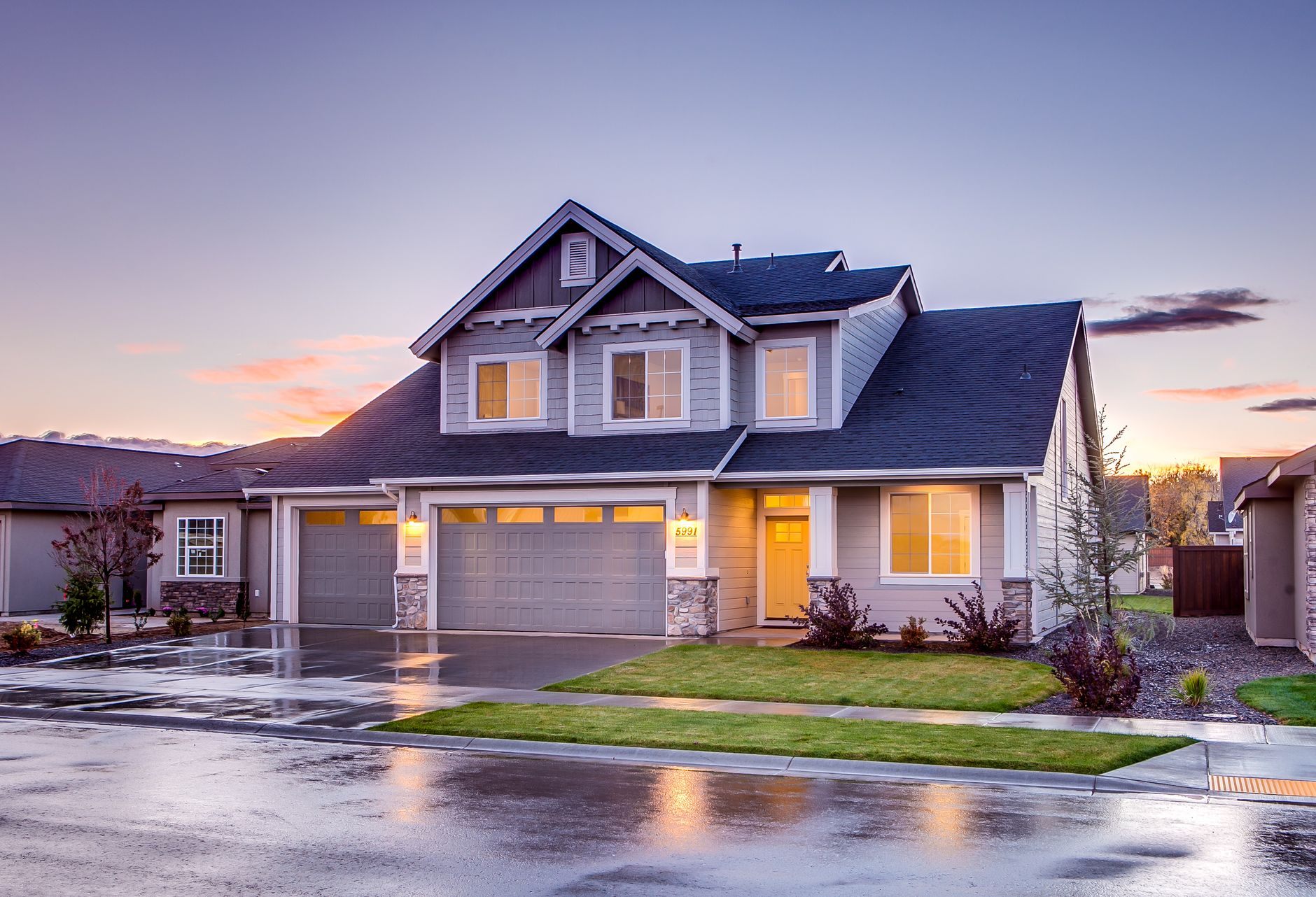 Craftsman-style house glowing at dusk with warm porch lights on