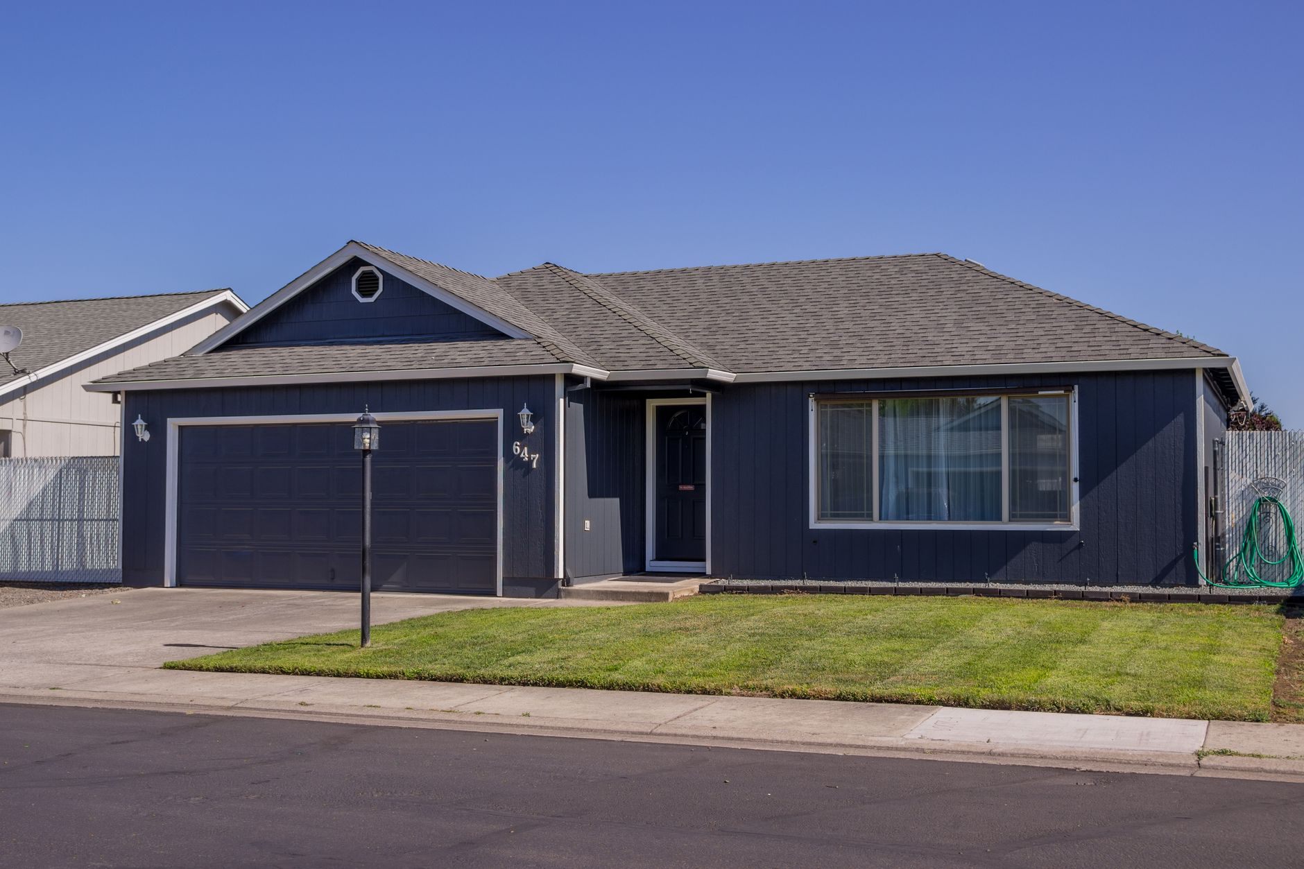 Navy blue single-story ranch house with a tidy front lawn on a quiet Oklahoma street