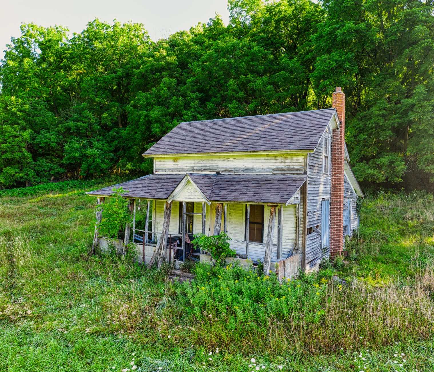 Weathered older home with a covered front porch awaiting repairs