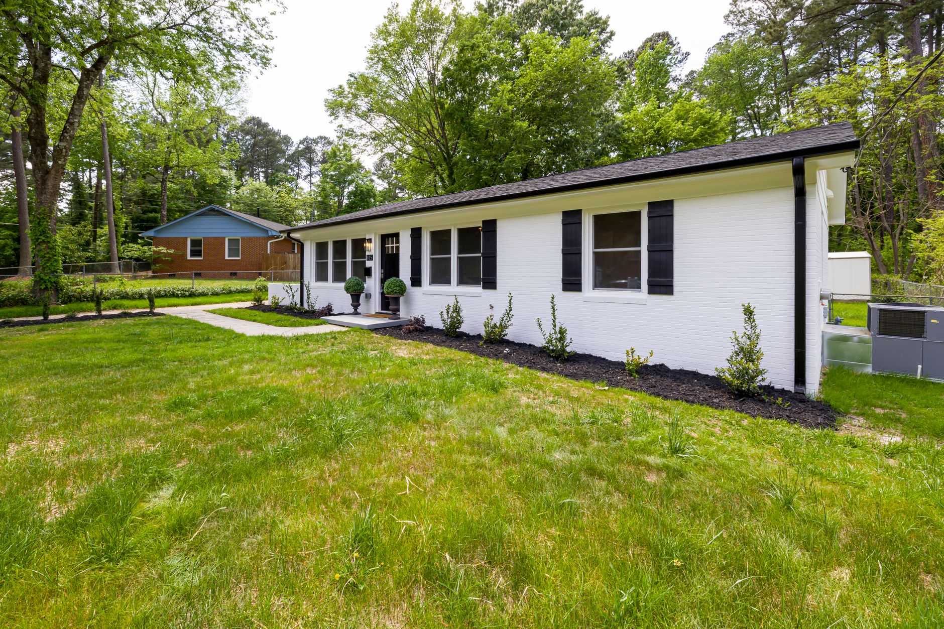White brick ranch house with a tidy front lawn, a classic Indianapolis postwar style